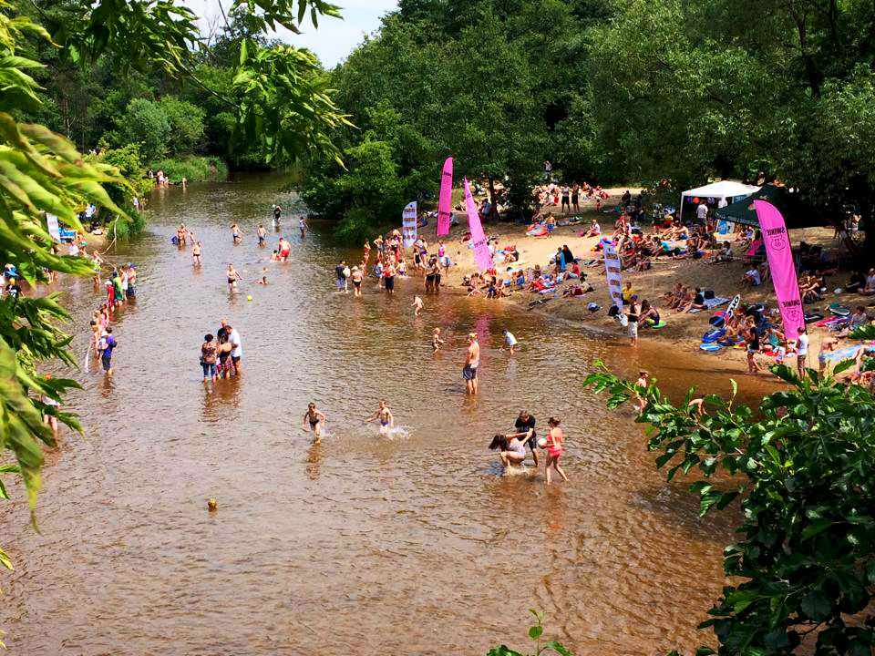 zdjęcie plaży nad rzeką i kąpiących się ludzi